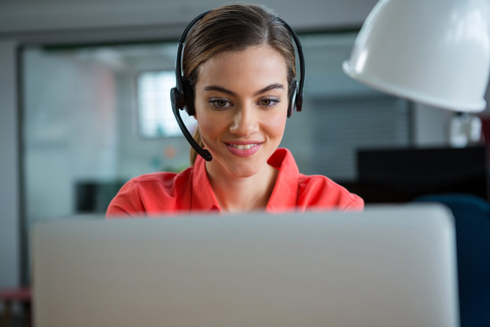 Contact centre agent with a headset working at her laptop