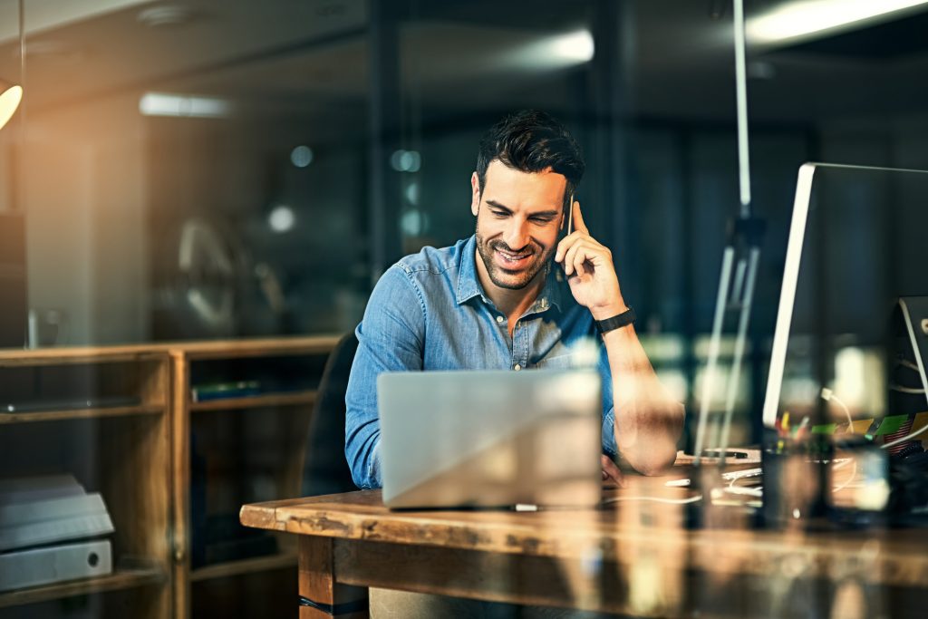 Small business owner taking a call on his mobile in his office